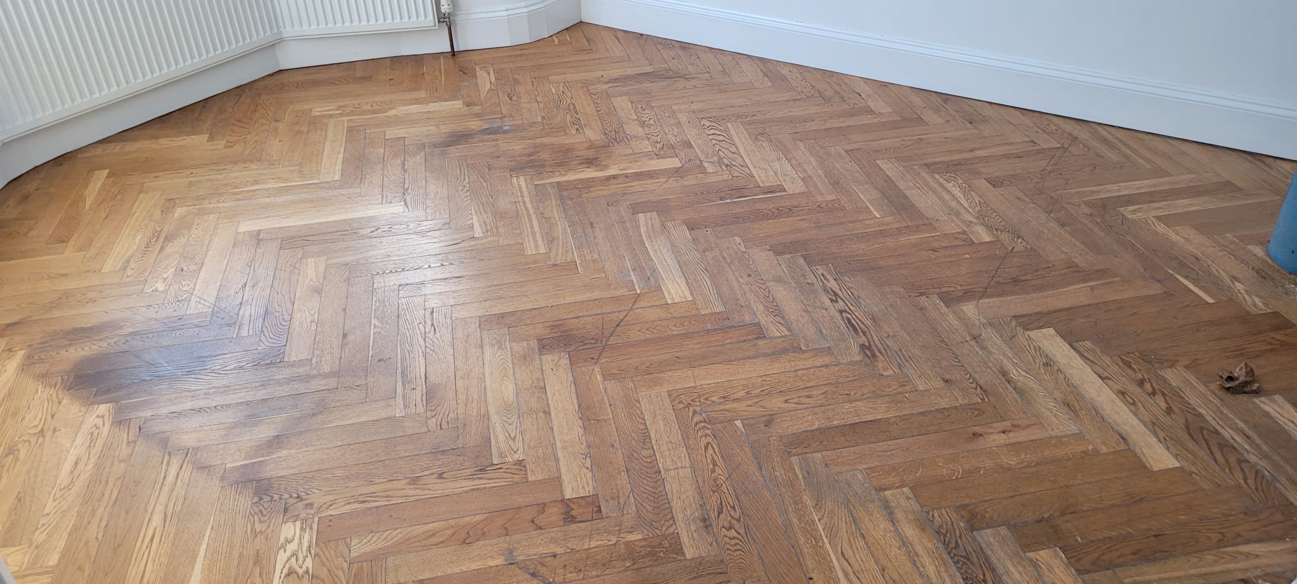 Wood Joyful Restoration in Lee: worn oak herringbone parquet (solid wood) floor before sanding, repairs and refinishing.