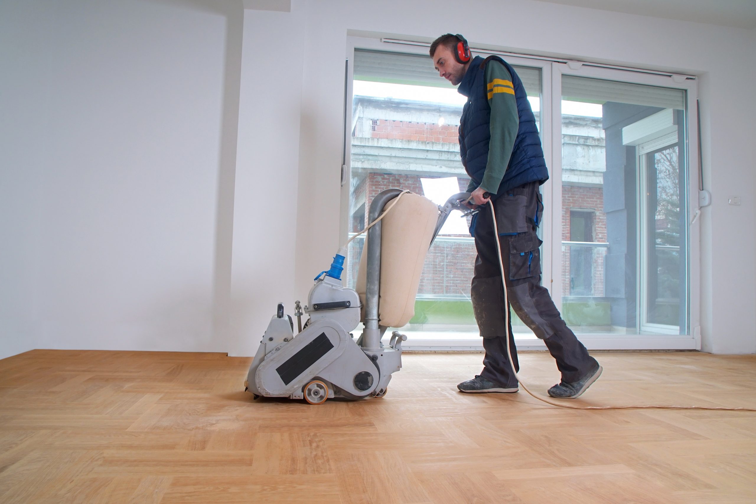 Wood Joyful Restoration in Lee: technician sanding an oak square parquet (solid wood) floor with a belt sander before refinishing.
