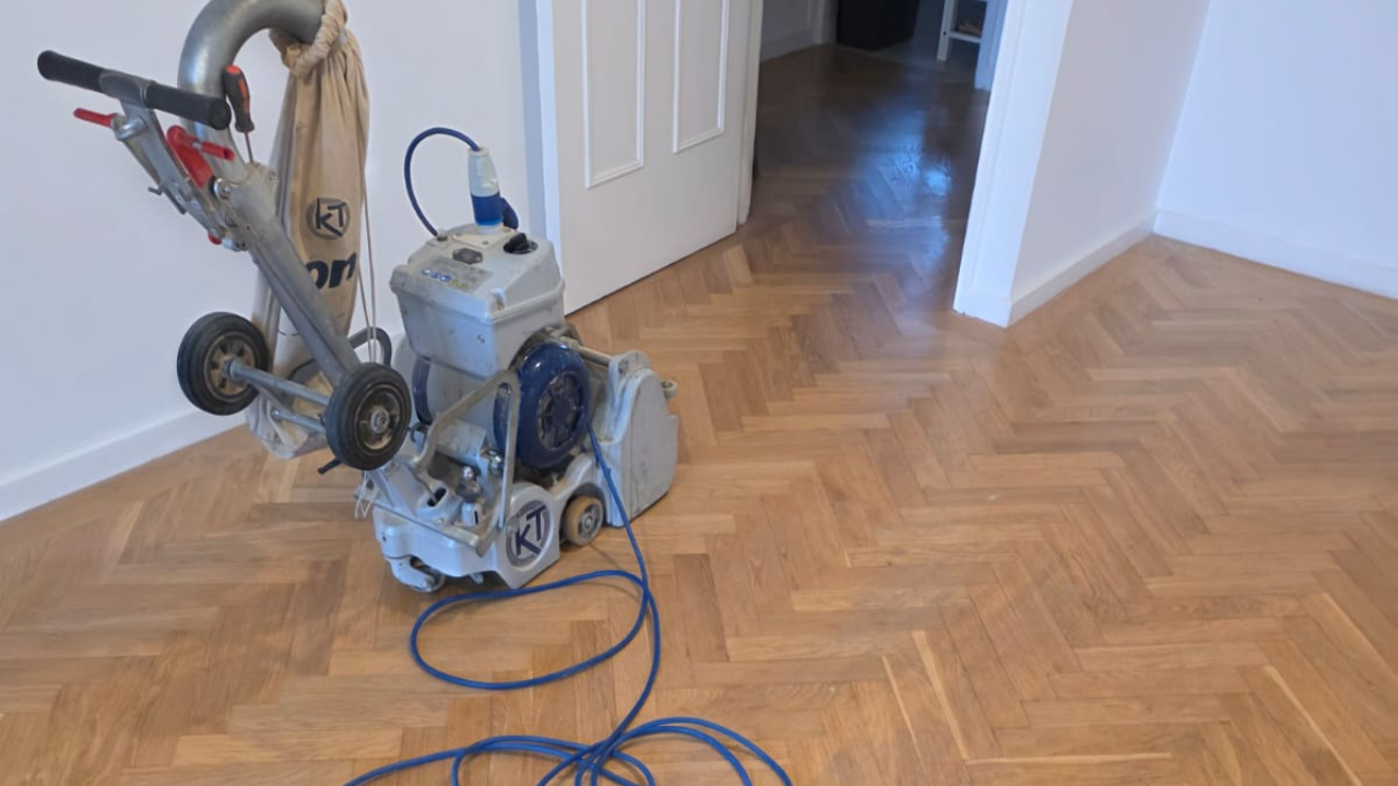 Parquet floor sanding in Lee on an oak herringbone parquet floor using a professional belt sander to restore the wood’s pattern and colour.