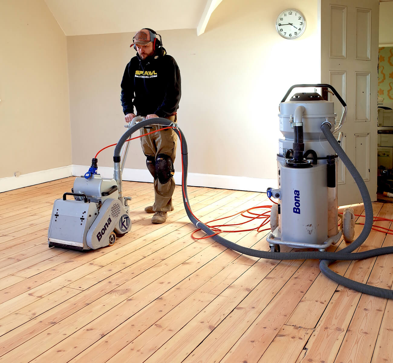 Wood Floor Sanding in Lee on pine softwood floorboards, with a technician using a dust-free Bona sanding machine to smooth the newly exposed timber surface.
