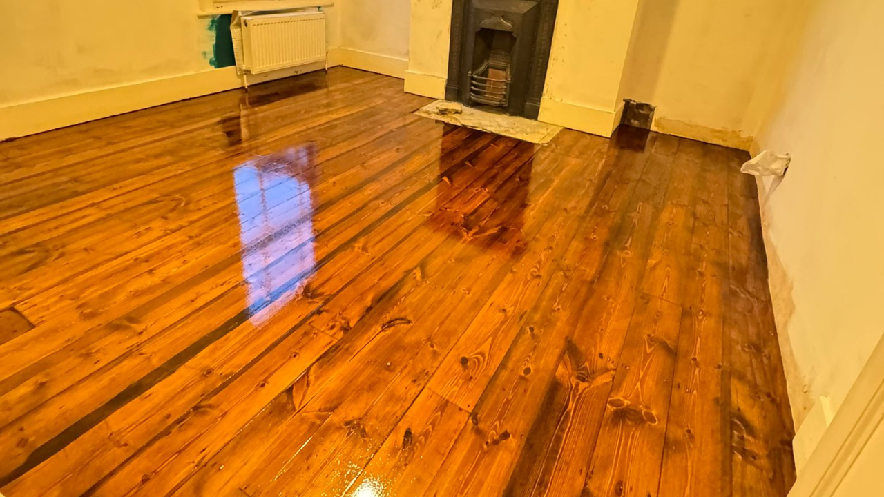 Wood Floor Sanding in Lee on gloss-stained pine floorboards, showing a living room with freshly restored wooden boards shining after refinishing.