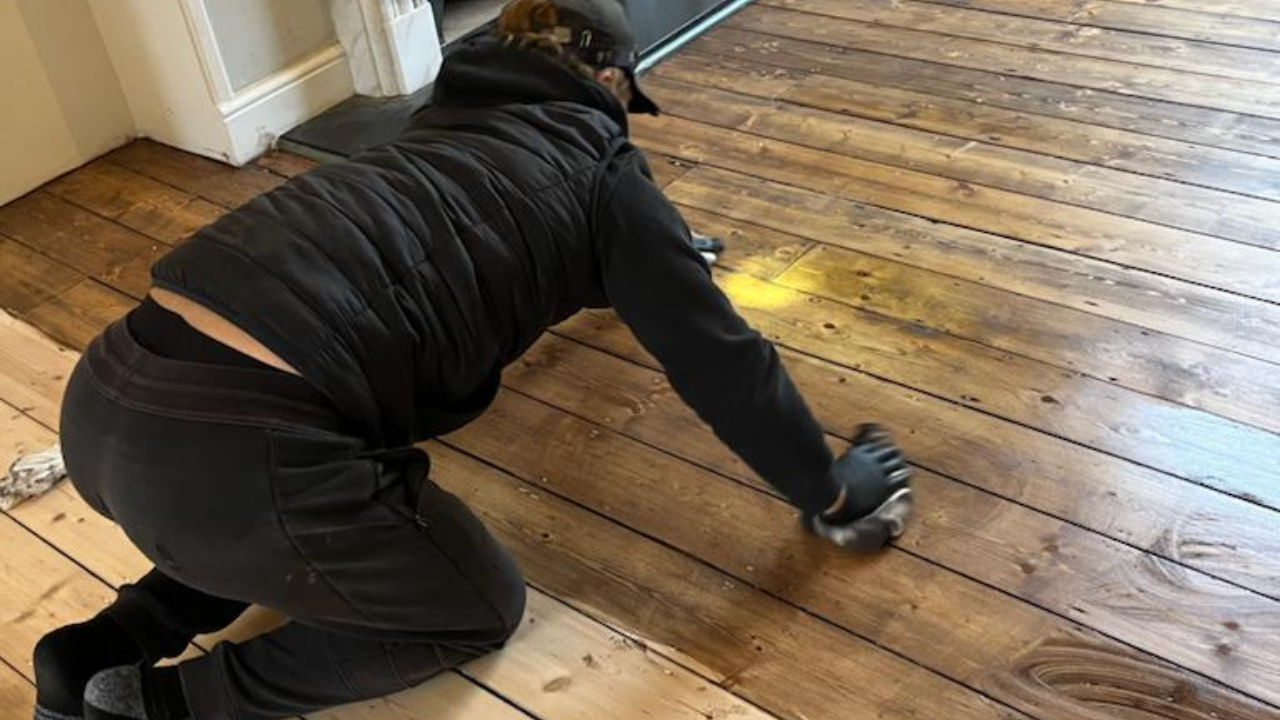 Wood Floor Sanding in Lee on Victorian pine softwood floorboards, with a technician hand-applying stain to the sanded wooden surface for an even finish.