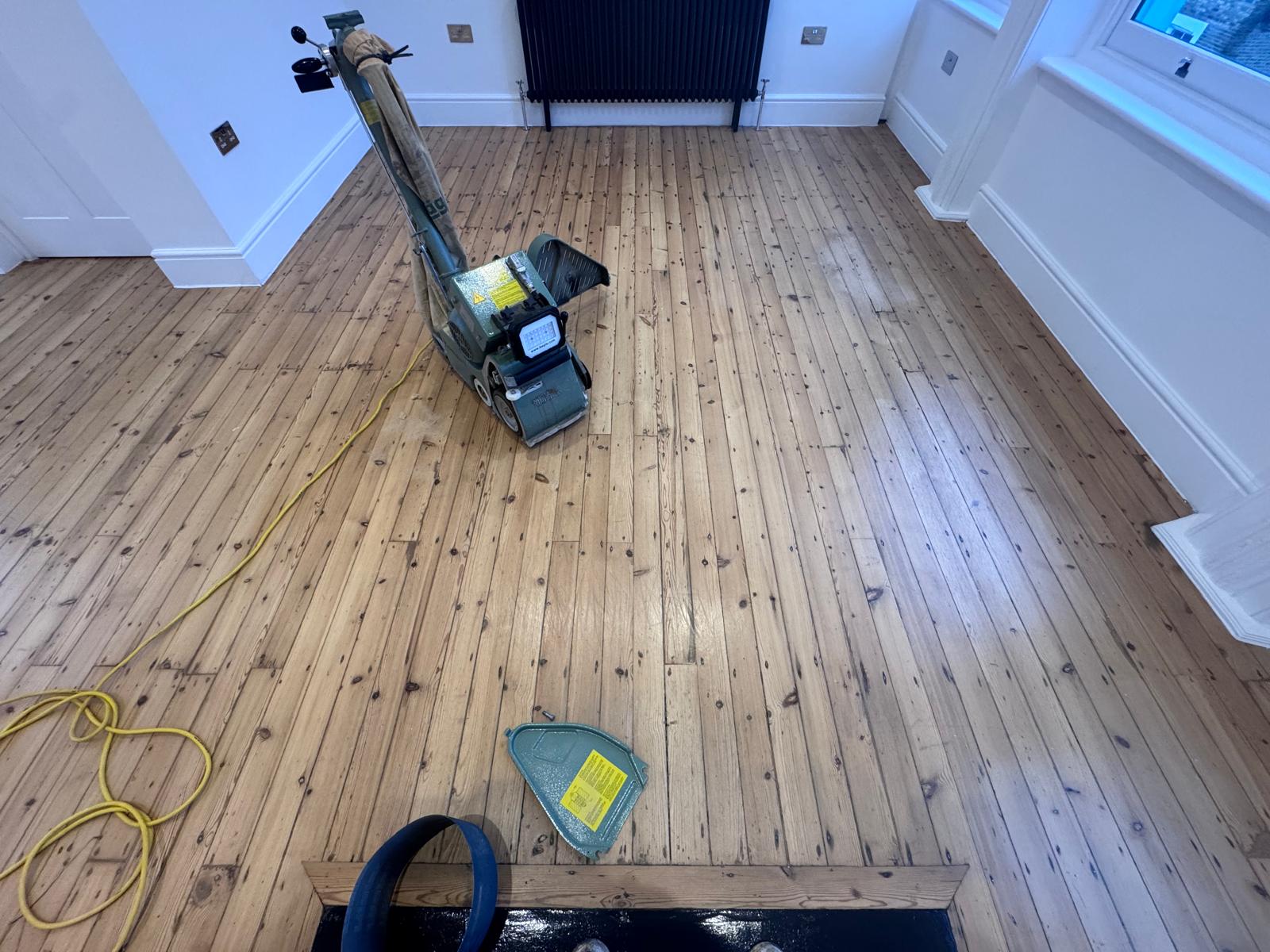 Wood Floor Sanding in Lee on narrow pine softwood floorboards, showing a professional sanding machine finishing a large living room floor.